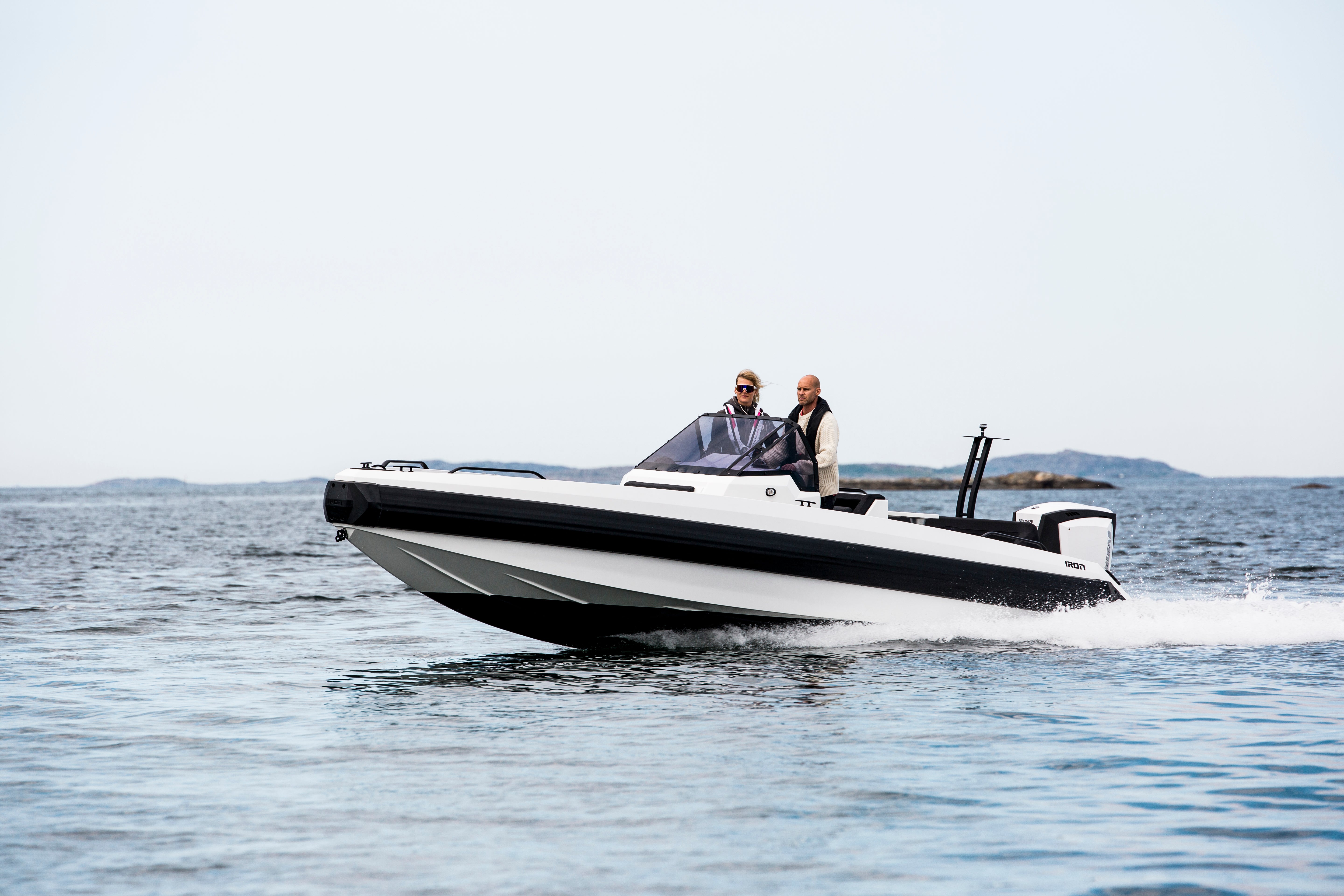 Two people on a black and white speedboat in the water boating central